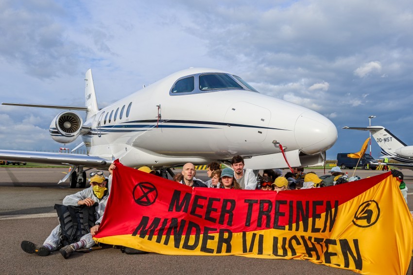 Activists holding up a banner in front of a private jet